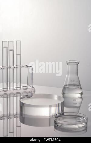 Lab theme with lab glassware and transparent podium on white background. Test tubes, petri dish and erlenmeyer flask filled transparent liquid. Space Stock Photo