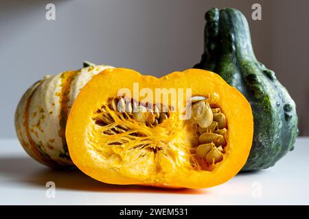 Cut and two whole pumpkins on a dark background on a white table Stock Photo