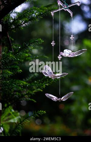 crystal butterfly pendants on a spruce branch in an alpine forest with bokeh in the background Stock Photo