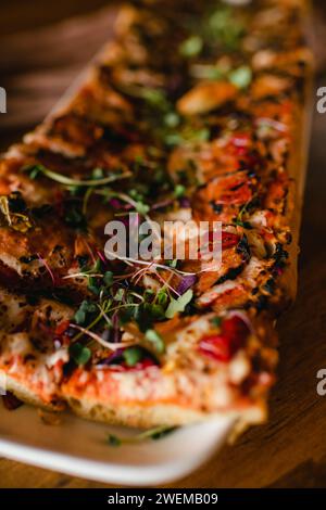 Close up of flatbread pizza with roasted peppers and sprouts Stock Photo