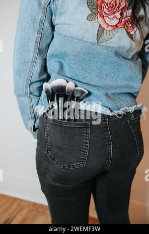 Makeup brushes tucked in the back pocket of stylish jeans Stock Photo