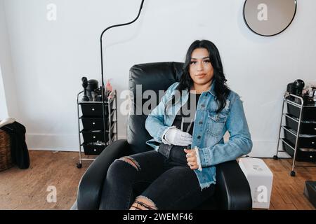 Hispanic woman in a salon chair, confidently holding eyelash tools Stock Photo
