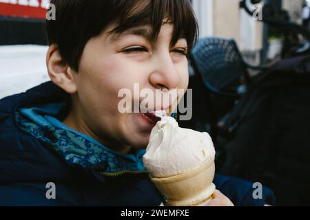 Young japanese boy enjoys eating ice cream outside ice cream shop Stock Photo