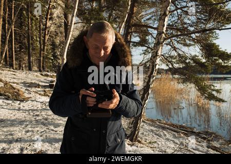 retired man looking at his camera by the lake in Sweden Stock Photo