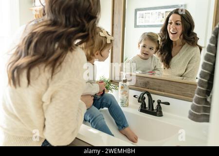 Mother and Daughter looking at Reflection in Mirror Stock Photo