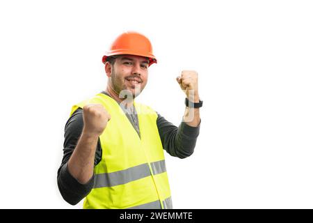 Male builder wearing orange safety hardhat and yellow fluorescent vest smiling as celebrating success making fists gesture with blank copyspace isolat Stock Photo