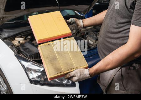 Auto mechanic shows old and new engine air filter for a passenger car Stock Photo