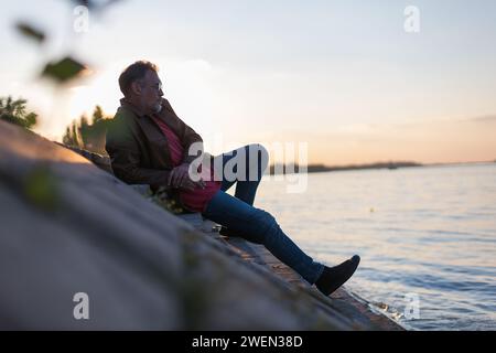 lonely man sitting on stairs next to the river bank Stock Photo