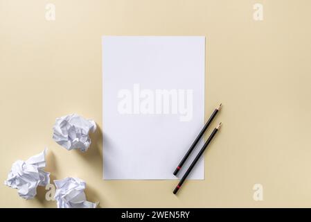 Blank writing sheet with pen and crumpled paper balls lay flat on yellow background Stock Photo