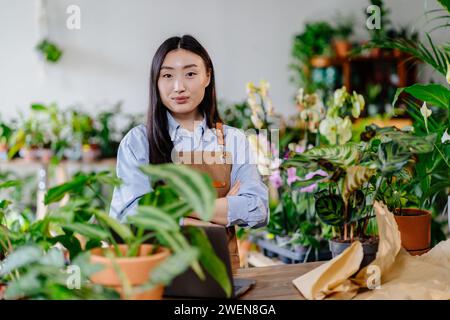 Small business, home decor concept. Professional young Asian female florist working on laptop. Stock Photo