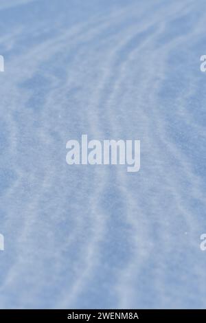 Snow after the wind forms a white canvas of swirling patterns. Light, sparkling, with ice crystals. A unique natural texture and the tranquility of th Stock Photo