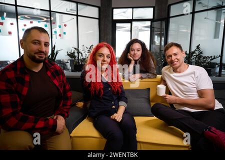 Self confident software developers sitting on cozy couches in lounge zone Stock Photo