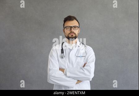 Portrait of serious young doctor standing with arms folded and looking at camera Stock Photo