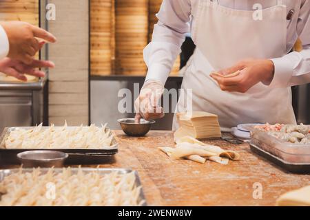 Close-up detail  of food prep at a Chinese restaurant kitchen as staff assemble dim sum dumplings in Taipei, Taiwan. Stock Photo