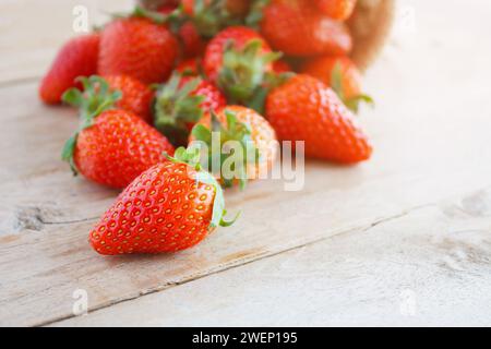 strawberries in small sack on wooden table background Stock Photo