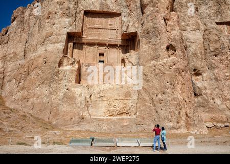 Tourists look at the rock-cut tomb of Darius II, Persian king (423-405 BC) of Achaemenid dynasty. Naqsh-e Rostam Necropolis near Persepolis, Iran. Stock Photo