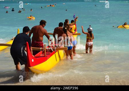 Waikiki Beach, HI, USA July 31, 2014 A team pushes an outrigger canoe into the waves of the Pacific Ocean, carrying tourists and adventurers on Waikik Stock Photo