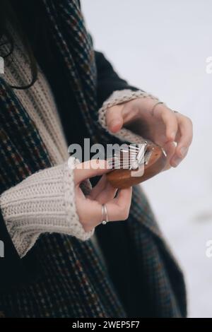 A person outdoors, holding a small acoustic music player in snowy weather Stock Photo