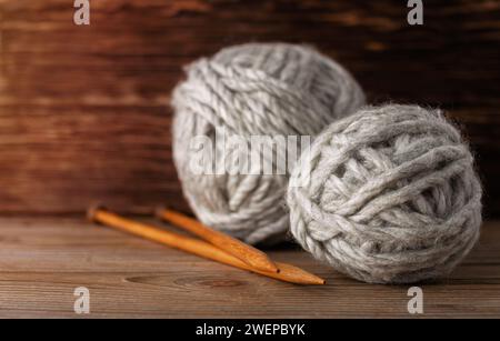 Balls of woolen yarn knitting needles on a wooden background. Knitting accessories. Stock Photo