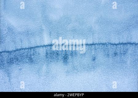 Frozen lake with a large crack on the surface from aerial top view. Natural winter background. Stock Photo