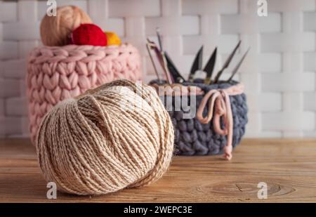 Closeup of knitting yarn with knitted baskets on wooden table. Concept of handmade. Stock Photo