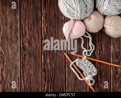 Balls of thread and knitting needles on a wooden background. Rustic style. Handmade knitted clothes. Stock Photo
