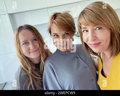 Cute mid adult women mother and her daughters making a selfie using smart phone at home Stock Photo