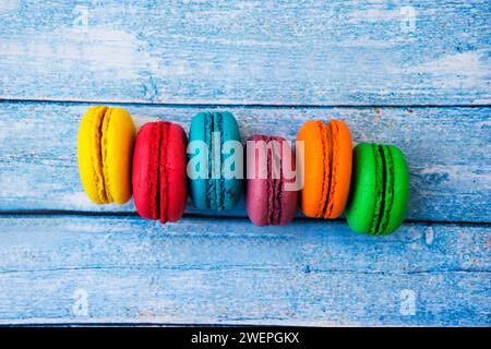 Topshot of sweet and colourful french macaroons on blue wooden background. Stock Photo