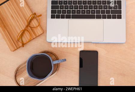 Overhead shot of laptop, coffee, and phone on desk Stock Photo