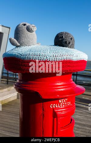 Yarn bombed post box on the end of Southend Pier, with grey seals knitted characters. Grey seals are often seen around the pier in the Thames Estuary Stock Photo