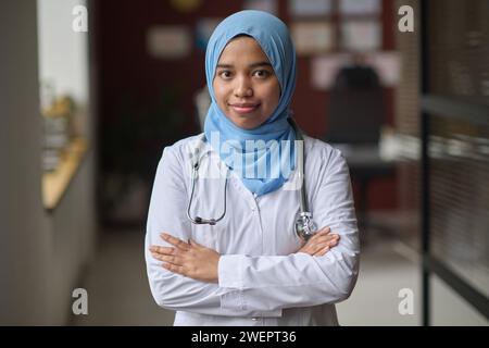 Female doctor in hijab standing at clinic with her arms crossed and confidently smiling at camera Stock Photo