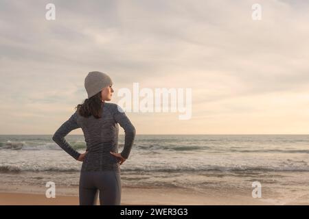 sporty woman runner, resting and looking out to sea after running at the beach Stock Photo