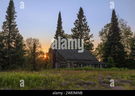 The sun setting behind an old cabin in northern Wisconsin. Stock Photo