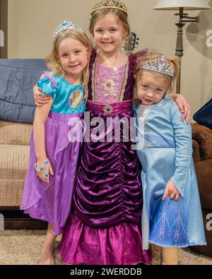 Three blonde & blue eyes small girls, children, dressed up in play costumes with costume jewelry tieras on their heads. USA. Stock Photo