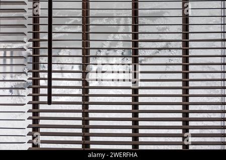 Ice crystals on window beyond venetian blinds. Stock Photo