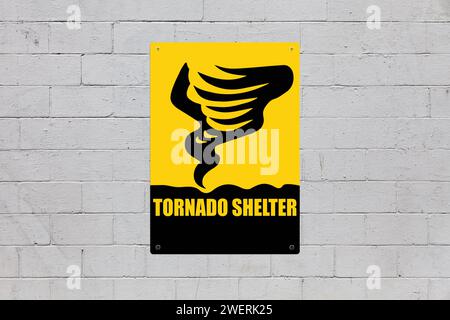 Yellow warning sign screwed to a brick wall to warn about a threat. In the middle of the panel, there is a tornado symbol and the message is saying 'C Stock Photo