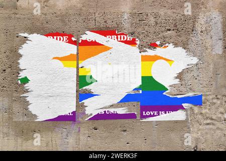 Full-frame weathered limestone wall with three torn rainbow posters in the middle depicting an heart sign with the message 'Gay pride - Love is univer Stock Photo