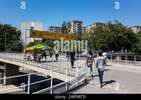 Pedestrians walking on the footbridge that links Maracana train station to Maracana stadium and the State University (UERJ) under summer blue sky. Stock Photo