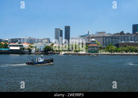 A small fishing vessel sailing on Guanabara bay waters, nearby Marechal Ancora square at Centro district coastline under summer afternoon blue sky. Stock Photo