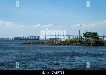 Distant view of Rio Niteroi bridge over Guanabara bay blue waters saw from Arariboia ferry station in Niteroi's Centro district under summer sunny day. Stock Photo