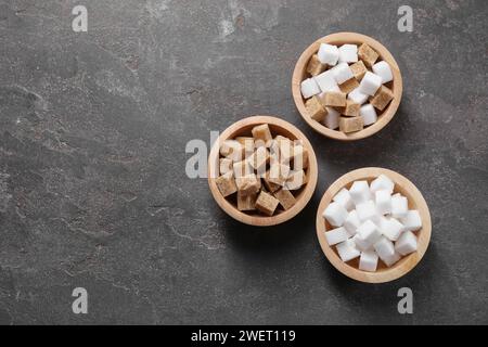 Different sugar cubes in bowls on gray textured table, flat lay. Space for text Stock Photo