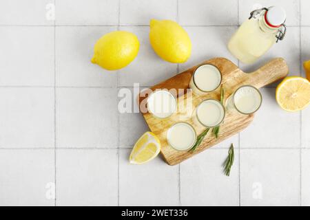 Board with shots of tasty Limoncello and rosemary on tile background Stock Photo