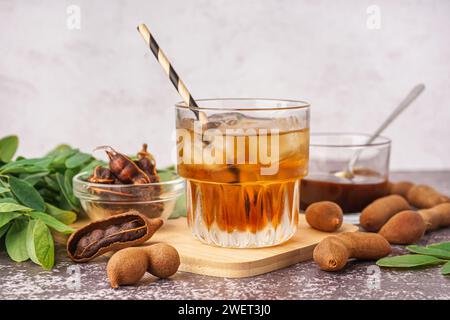 Glass of tasty tamarind drink and fruits on table Stock Photo