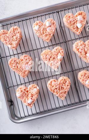 Pink heart shaped rice krispie treats on a cooling rack, homemade sweet treat for Valentines Day Stock Photo