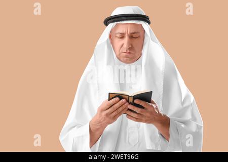 Muslim man reading Koran on beige background Stock Photo