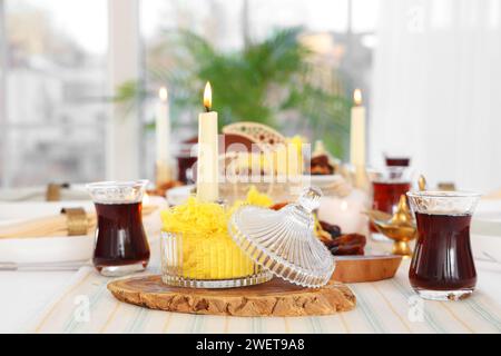 Table setting with traditional Eastern dishes and burning candles for Ramadan in room, closeup Stock Photo