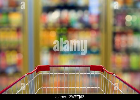Shopping cart with convenience store refrigerator shelves blurred background Stock Photo