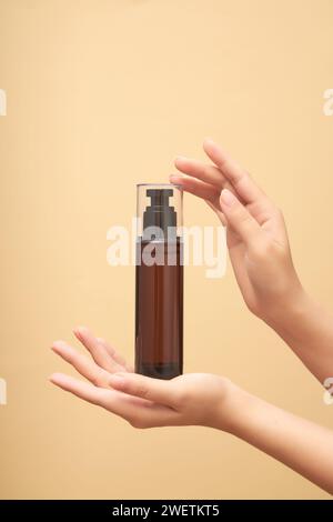 Mockup of cosmetics in the form of toner bottles or hair sprays cradled in women's hands on beige background. Advertising photo for cosmetic, space fo Stock Photo