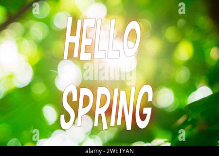 Green blurred background with white text Hello, spring. Selective focus Stock Photo