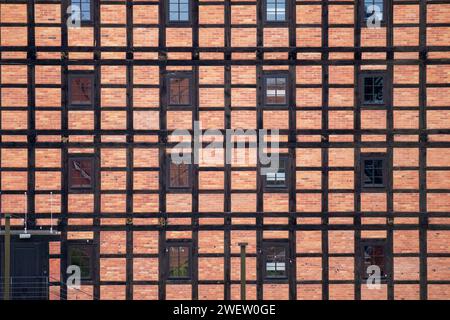 a row of vertical and horizontal windows in a red brick and timber frame wall Stock Photo